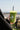 a woman holding a green earthbar smoothie, skyline and blue sky in the background