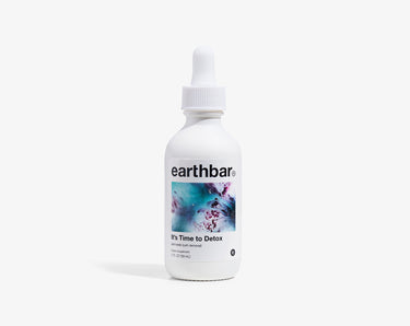 A bottle of 'It's Time To Detox' herbal tonic by earthbar, with a dropper cap.