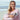 A woman holding a Barebells protein bar on the beach.