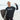 A man holding a Barebells protein bar and a surfboard on the beach.