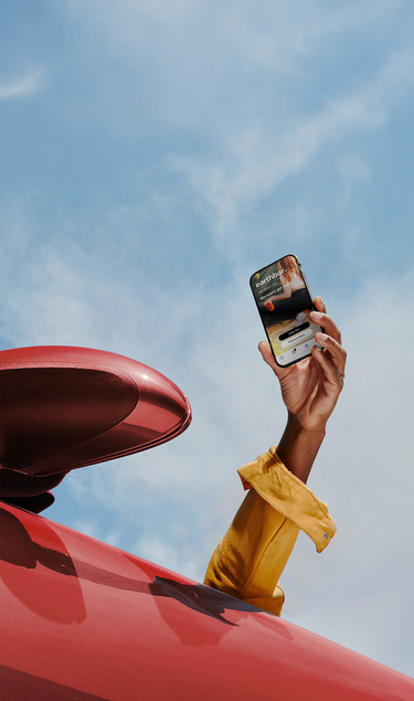man holding a phone with the earthbar app out the window of a red car 