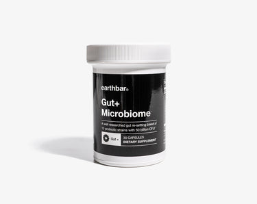 A container of Earthbar Gut + Microbiome probiotic supplement with 50 billion CFU per serving, 10 probiotic strains, in a black and white label format.