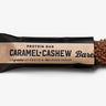 A Barebells protein bar packaging with the text 'Caramel Cashew' and an image of cashew nuts on the front, indicating 20 grams of protein and no added sugar.